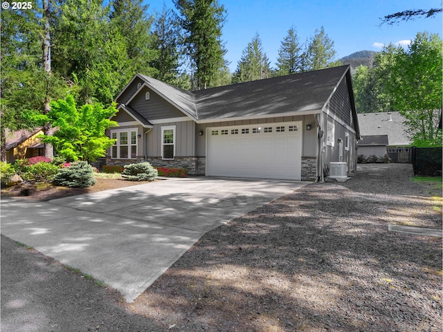 64911 E Mountain Meadow Ln, Rhododendron, OR 97049 - view of front facade featuring stone siding, an attached garage, board and batten siding, concrete driveway, and central air condition unit