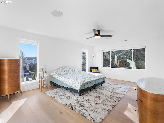 bedroom featuring multiple windows, ceiling fan, and light wood-type flooring