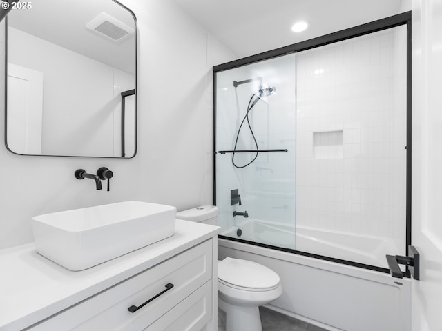 full bathroom with vanity, bath / shower combo with glass door, and toilet