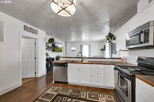 kitchen with white cabinets, sink, butcher block counters, and stainless steel appliances