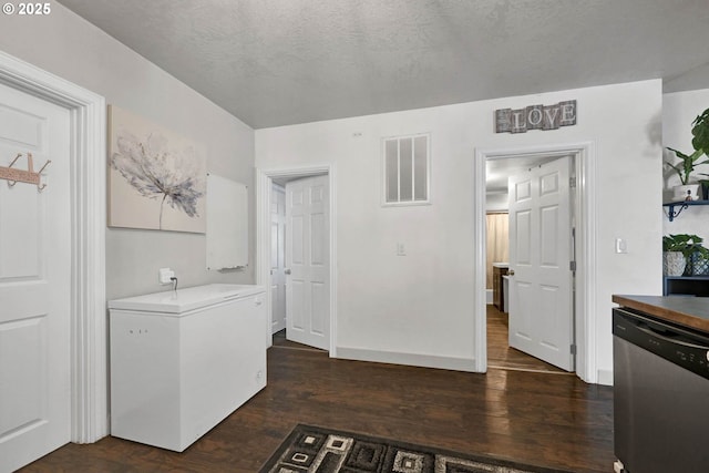 laundry area featuring a textured ceiling and dark wood-type flooring