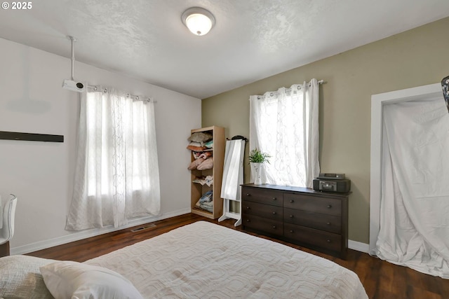 bedroom featuring multiple windows and dark hardwood / wood-style flooring