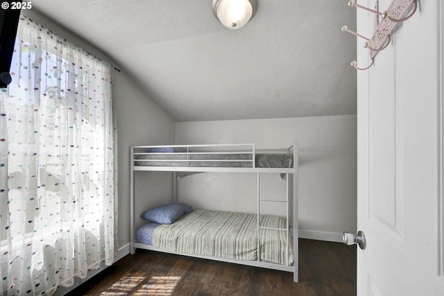 unfurnished bedroom with lofted ceiling and dark wood-type flooring