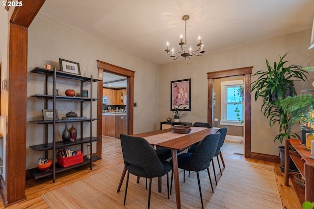 dining area with a notable chandelier, light wood-style flooring, and baseboards