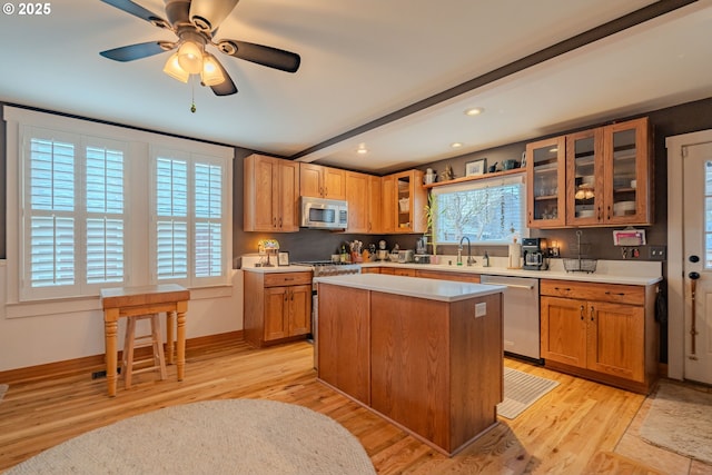 kitchen with stainless steel appliances, a kitchen island, light countertops, and glass insert cabinets