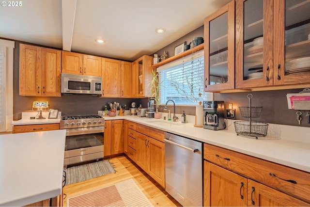 kitchen featuring stainless steel appliances, light countertops, and glass insert cabinets