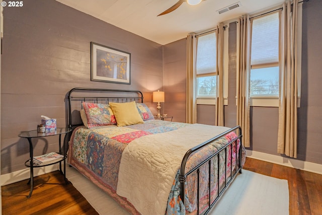 bedroom with dark wood-style floors, ceiling fan, visible vents, and baseboards