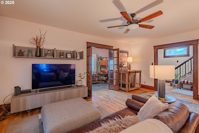 living room with light wood finished floors, stairs, and a ceiling fan