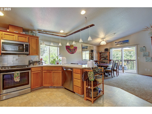 kitchen featuring appliances with stainless steel finishes, brown cabinetry, a textured ceiling, and a wealth of natural light