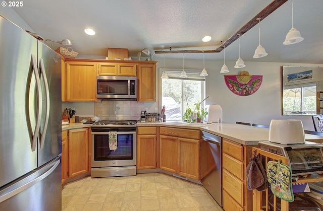 kitchen with appliances with stainless steel finishes, light countertops, a peninsula, decorative light fixtures, and recessed lighting