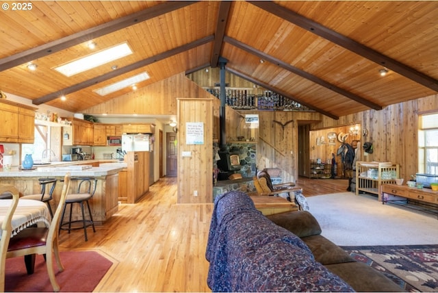 62482 Canyon Creek Ln, Canyon City, OR 97820 - living room featuring wooden walls, light wood-style floors, wood ceiling with exposed beams, a skylight, and a wood stove