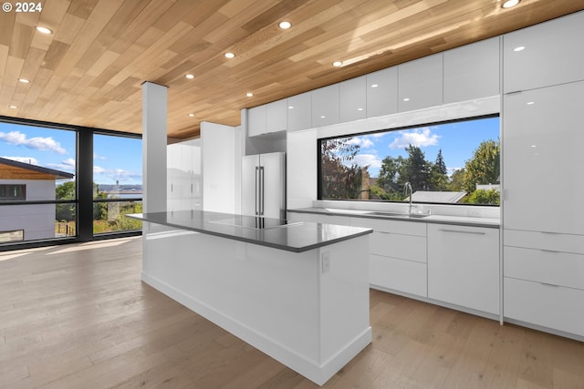 kitchen with modern cabinets, a sink, white cabinets, wooden ceiling, and high quality fridge