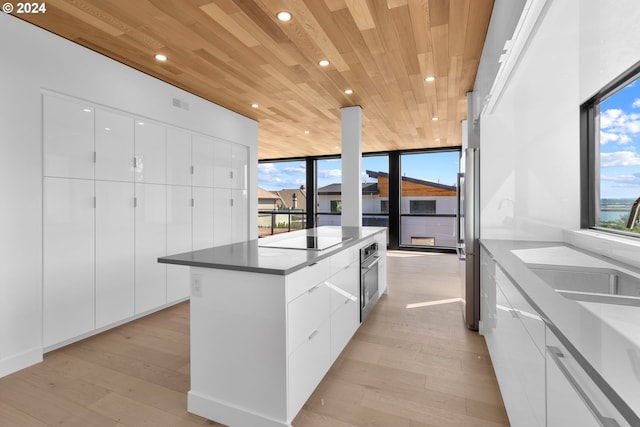 kitchen featuring light wood-type flooring, modern cabinets, wooden ceiling, and a center island