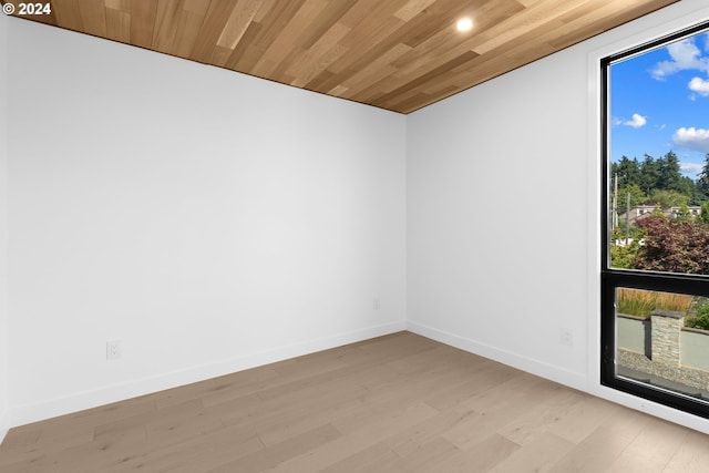 unfurnished room featuring baseboards, light wood-style floors, and wood ceiling