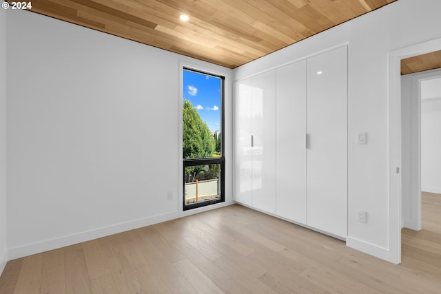 unfurnished bedroom with wooden ceiling, baseboards, and light wood-style floors