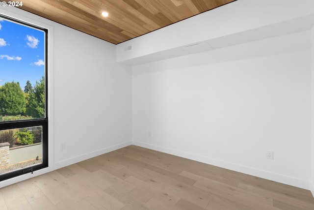 empty room with wood ceiling, light wood-style floors, and baseboards