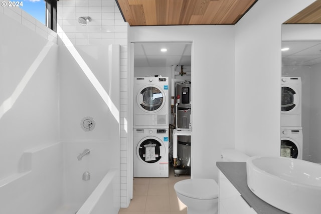 bathroom featuring stacked washing maching and dryer, bathtub / shower combination, wood ceiling, tile patterned floors, and toilet