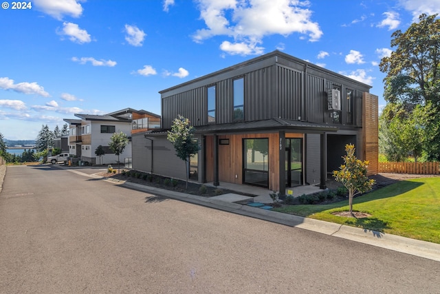 exterior space with a standing seam roof, a front lawn, and fence