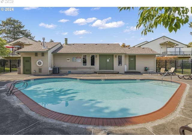 pool with entry steps, a patio area, fence, and central AC