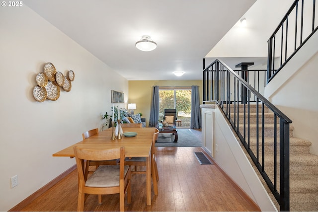 dining room featuring visible vents, baseboards, hardwood / wood-style floors, and stairway