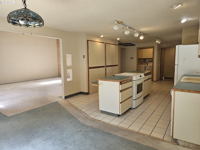 710 E Quince Ave, Hermiston, OR 97838 - kitchen featuring white appliances, washer and dryer, a center island, a textured ceiling, and a sink