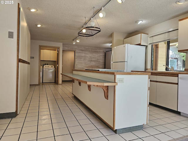 kitchen featuring white appliances, white cabinetry, a textured ceiling, rail lighting, and a kitchen breakfast bar