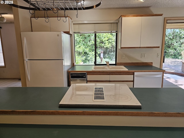 710 E Quince Ave, Hermiston, OR 97838 - kitchen with white appliances, a sink, rail lighting, a textured ceiling, and a kitchen island