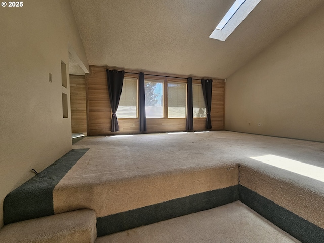 carpeted empty room featuring lofted ceiling, a skylight, and a textured ceiling