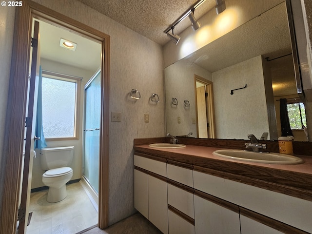 full bath with a textured ceiling, toilet, a stall shower, and double vanity