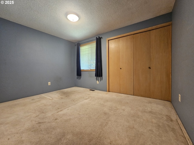 unfurnished bedroom with carpet flooring, a closet, and a textured ceiling