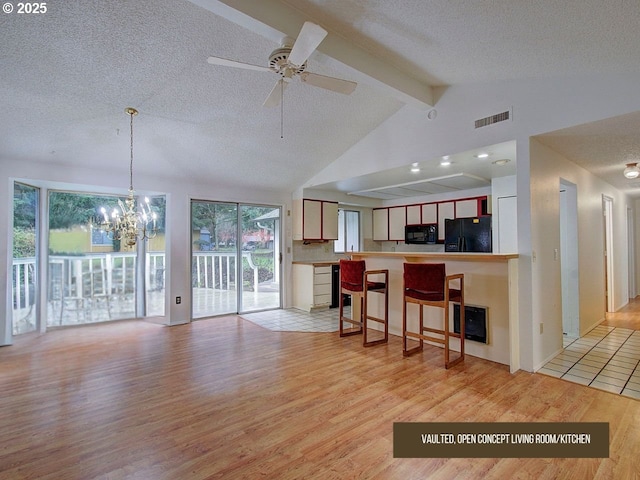 kitchen with beam ceiling, a textured ceiling, light hardwood / wood-style flooring, and black appliances