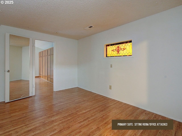 unfurnished room featuring light hardwood / wood-style flooring and a textured ceiling