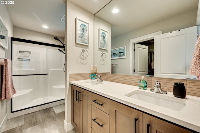 bathroom featuring a stall shower, backsplash, and a sink