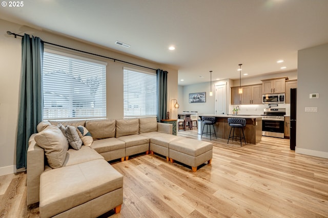 living room with light wood-type flooring, visible vents, baseboards, and recessed lighting