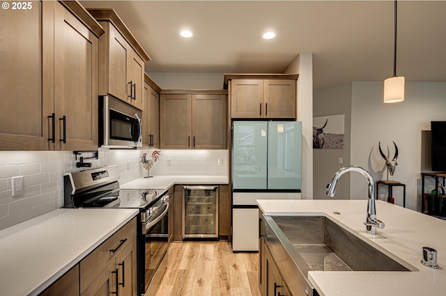 kitchen featuring a sink, stainless steel appliances, wine cooler, light wood-style floors, and tasteful backsplash