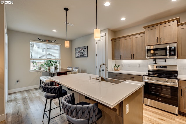 kitchen with a sink, a kitchen breakfast bar, tasteful backsplash, and stainless steel appliances