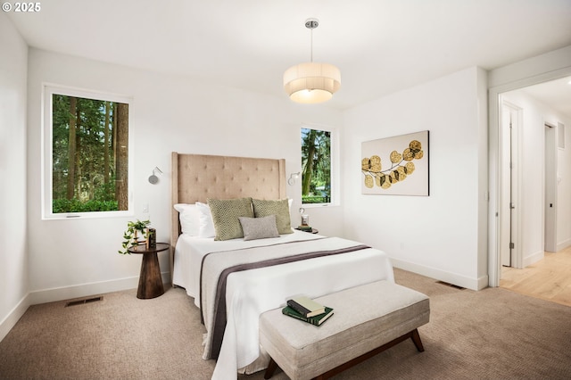 bedroom with visible vents, baseboards, and light colored carpet