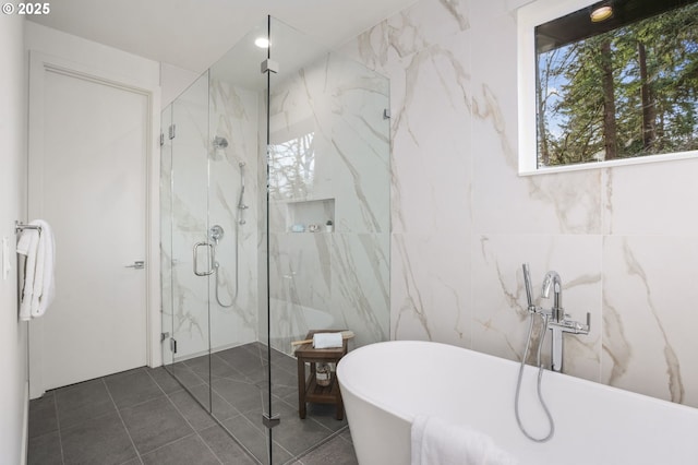 bathroom featuring a soaking tub, tile patterned floors, tile walls, and a marble finish shower