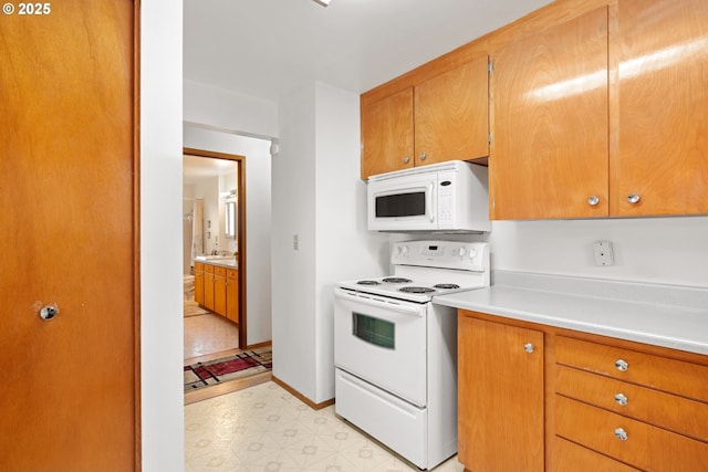 kitchen with light floors, light countertops, brown cabinetry, a sink, and white appliances