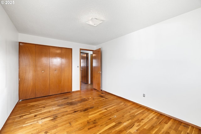 unfurnished bedroom with light wood-type flooring, a closet, and a textured ceiling