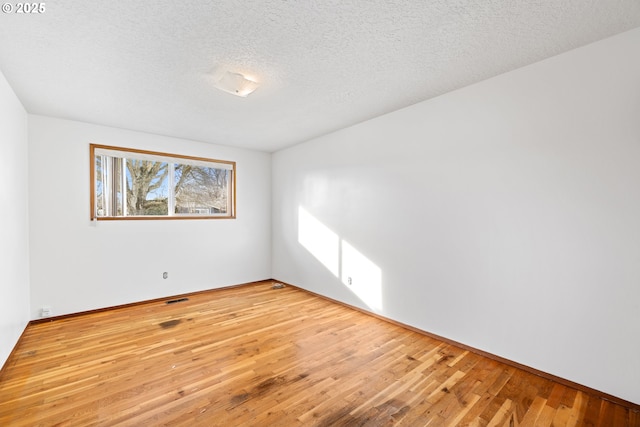 spare room with a textured ceiling, visible vents, and light wood-style floors