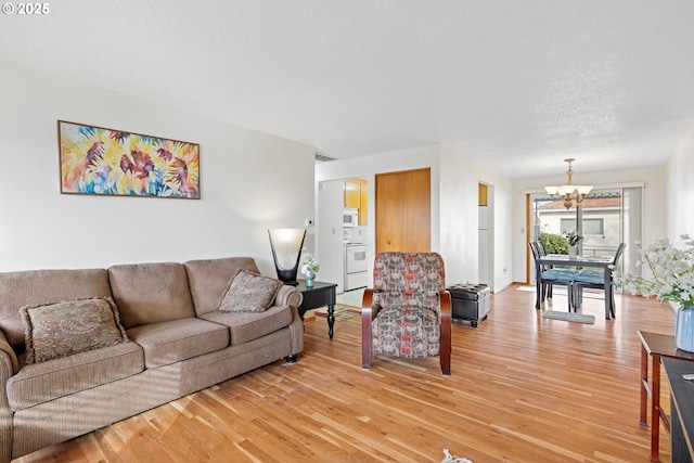 living room with a chandelier, visible vents, a textured ceiling, and wood finished floors