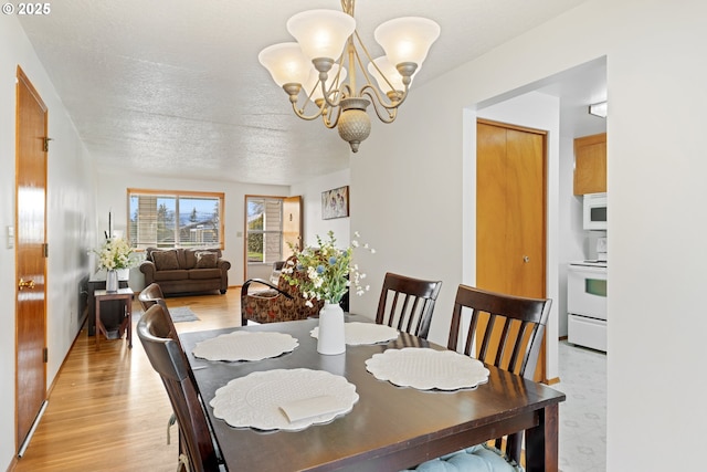 dining area featuring a chandelier, light wood-style floors, and a textured ceiling