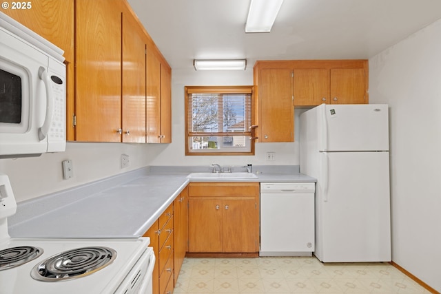 kitchen with a sink, white appliances, light countertops, and light floors