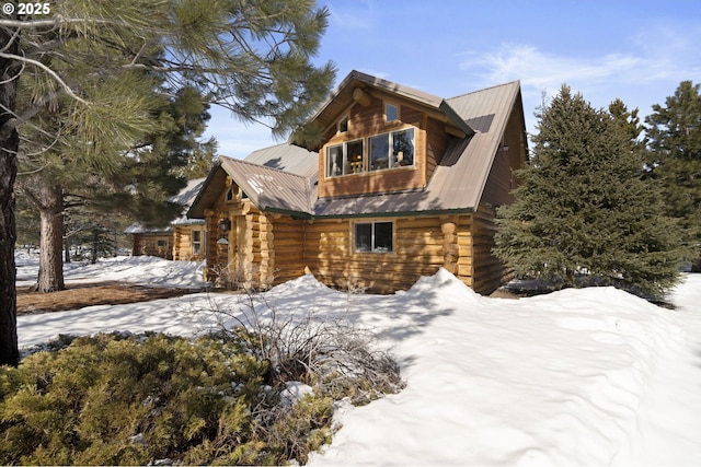 snow covered property featuring log siding and metal roof