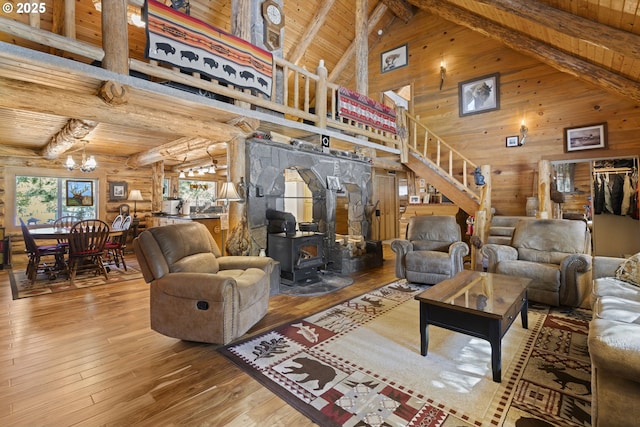 living area with wooden ceiling, hardwood / wood-style flooring, stairs, beamed ceiling, and a wood stove