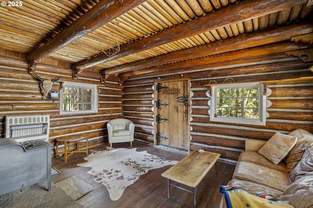 living room featuring healthy amount of natural light, heating unit, beamed ceiling, hardwood / wood-style flooring, and rustic walls