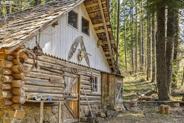 view of side of home featuring a barn, log exterior, and an outdoor structure
