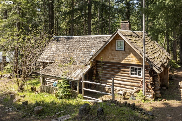 view of home's exterior with log siding and a chimney
