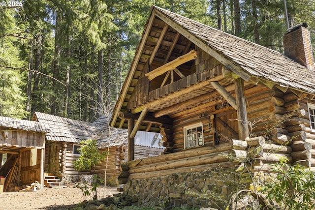 view of side of home with log exterior and a chimney